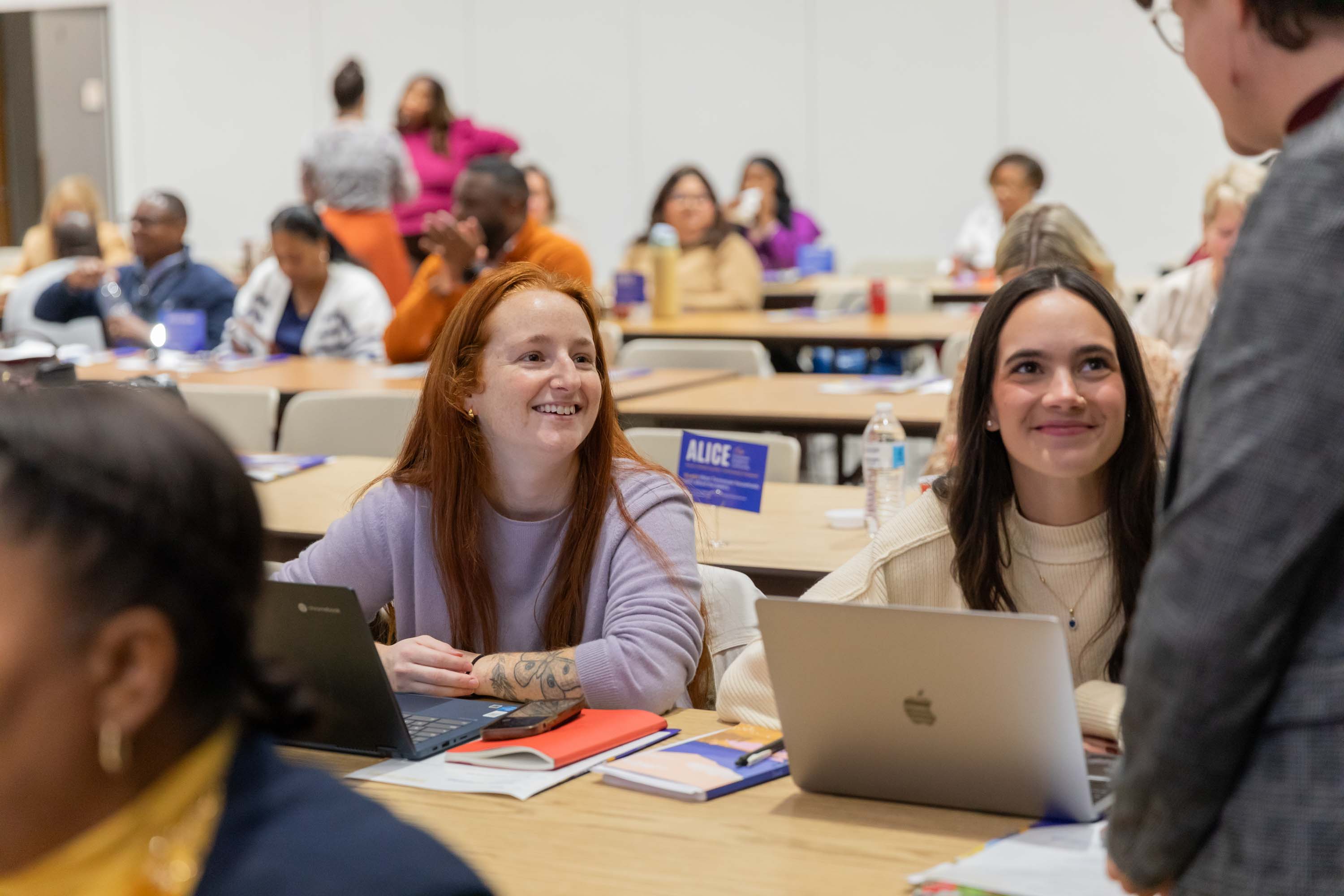 Two young ladies are talking with one of the speakers.