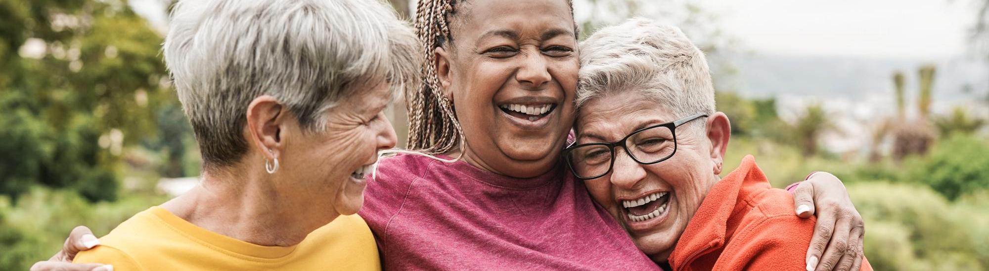 Three women are smiling and hugging.