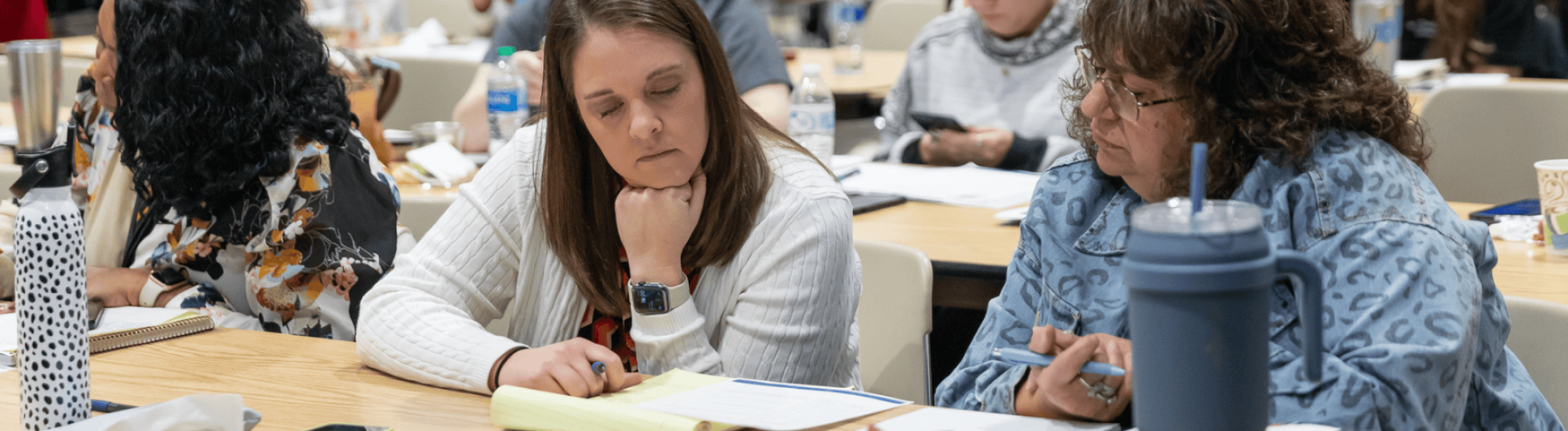 Two women are taking notes at a conference.