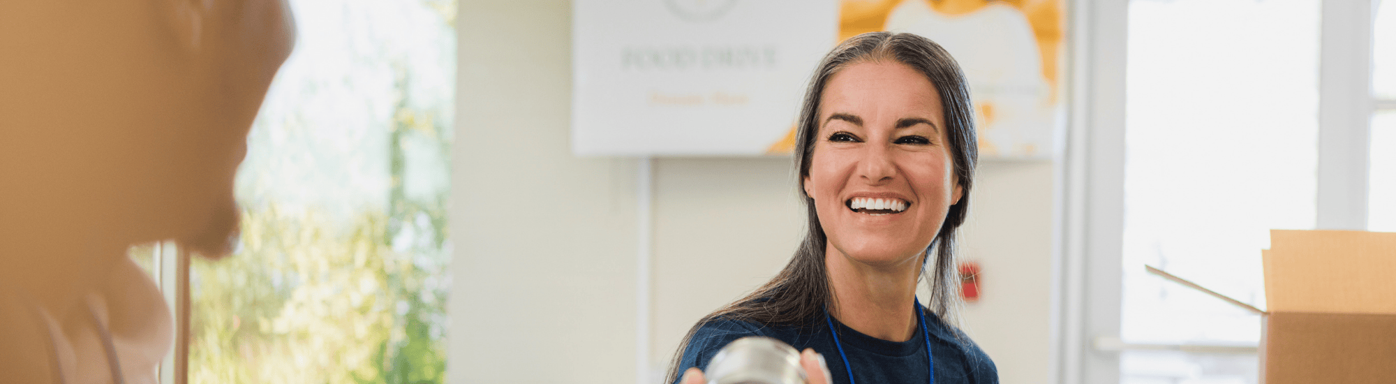 A woman is handing a can of food to someone.