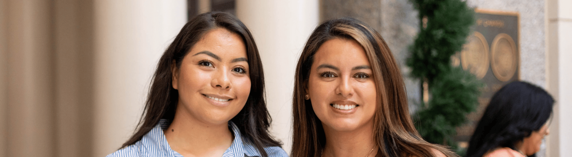 Two Hispanic women are smiling at the camera.