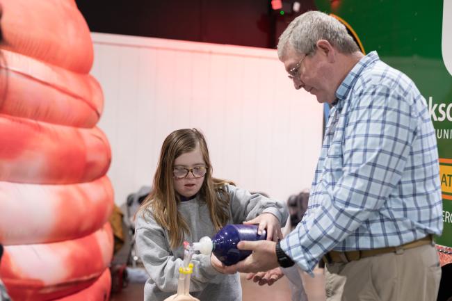 A girl learning how to use a bag valve mask.